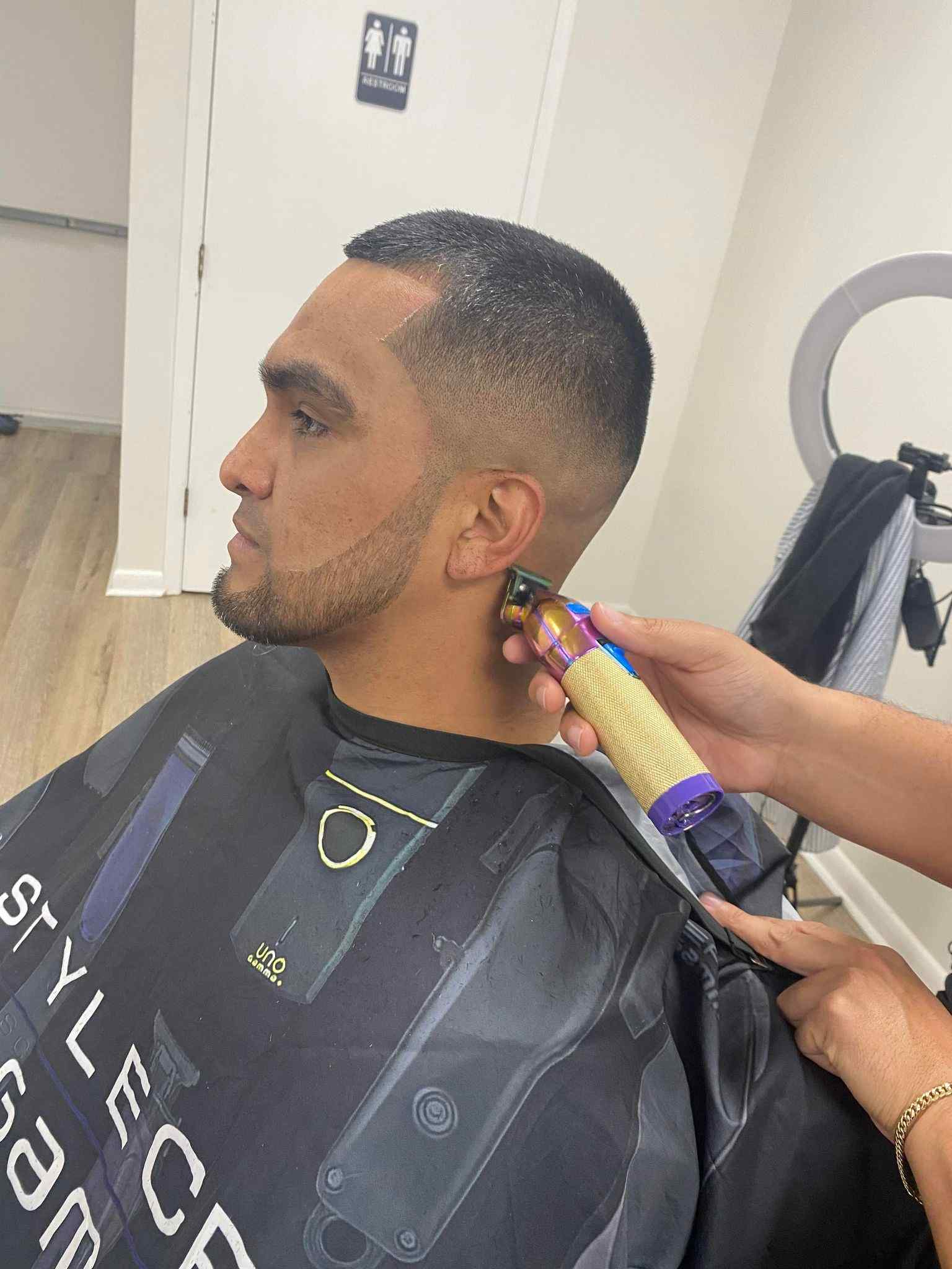 Barber trimming hair around the ear with clippers in Lake Wales