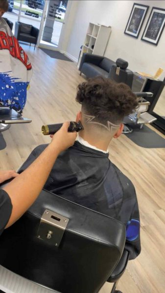 A person gets their hair trimmed in a barber shop in Bartow, Florida. The back of their hair features a zigzag design.